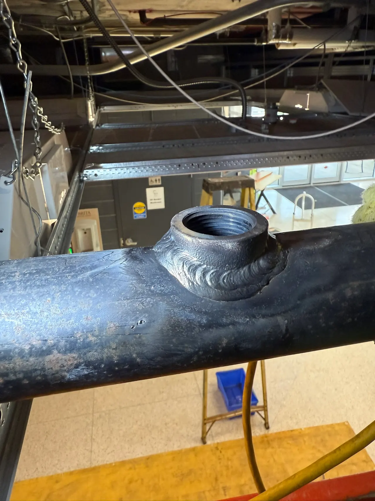 Close-up of a welded O-let branch connection on carbon steel pipe