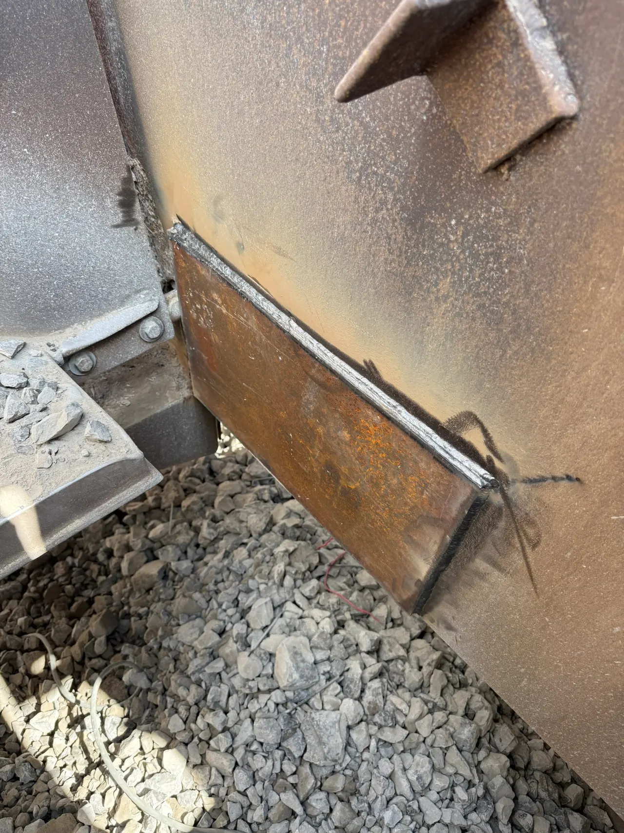Close view of a welded steel plate repair on heavy equipment